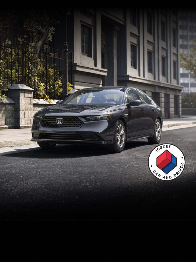 2026 Honda Accord LX in Meteorite Gray Metallic parked on a city street with overlapping Car and Driver 10Best logo (Mid-Size Sedan).