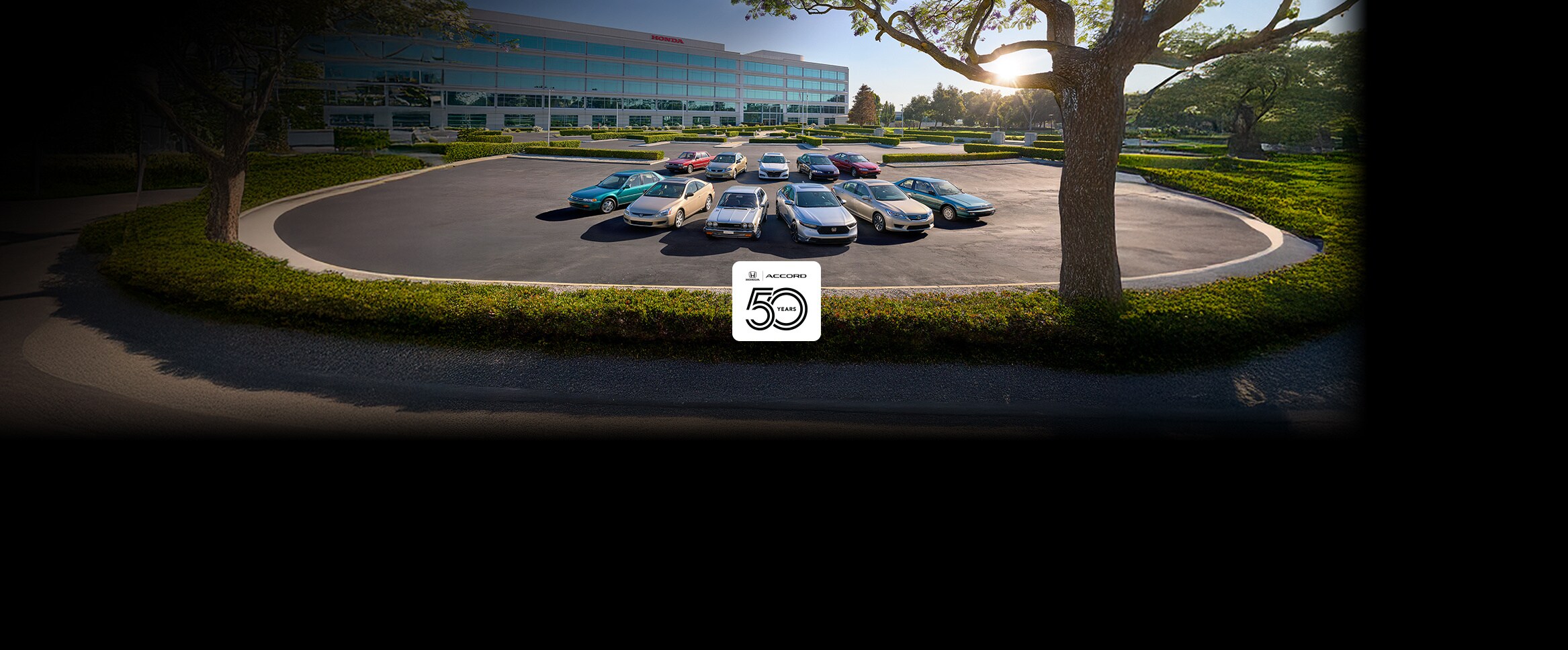 Honda Accord models front view parked in a lot in front of a corporate building at sunset.