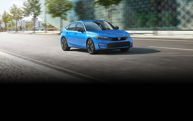 2026 Honda Civic Hatchback Sport Touring Hybrid in Boost Blue Pearl front view driving on a city street (Compact Hatchback).