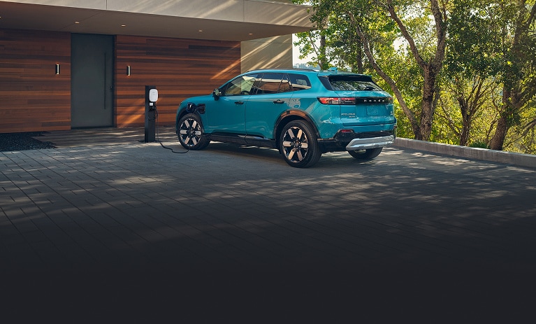 North Shore Pearl色的2026 Honda Prologue Elite正在車道上家用充電樁充電的背面視角（純電SUV）。