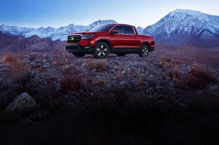 2026 Ridgeline in Radian Red Metallic, parked in front of a snowy mountain